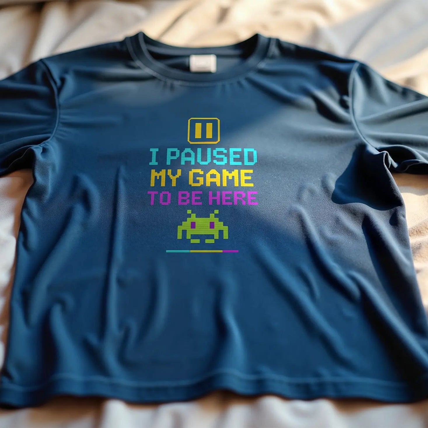 Blue t-shirt with text and pixelated design on a bed