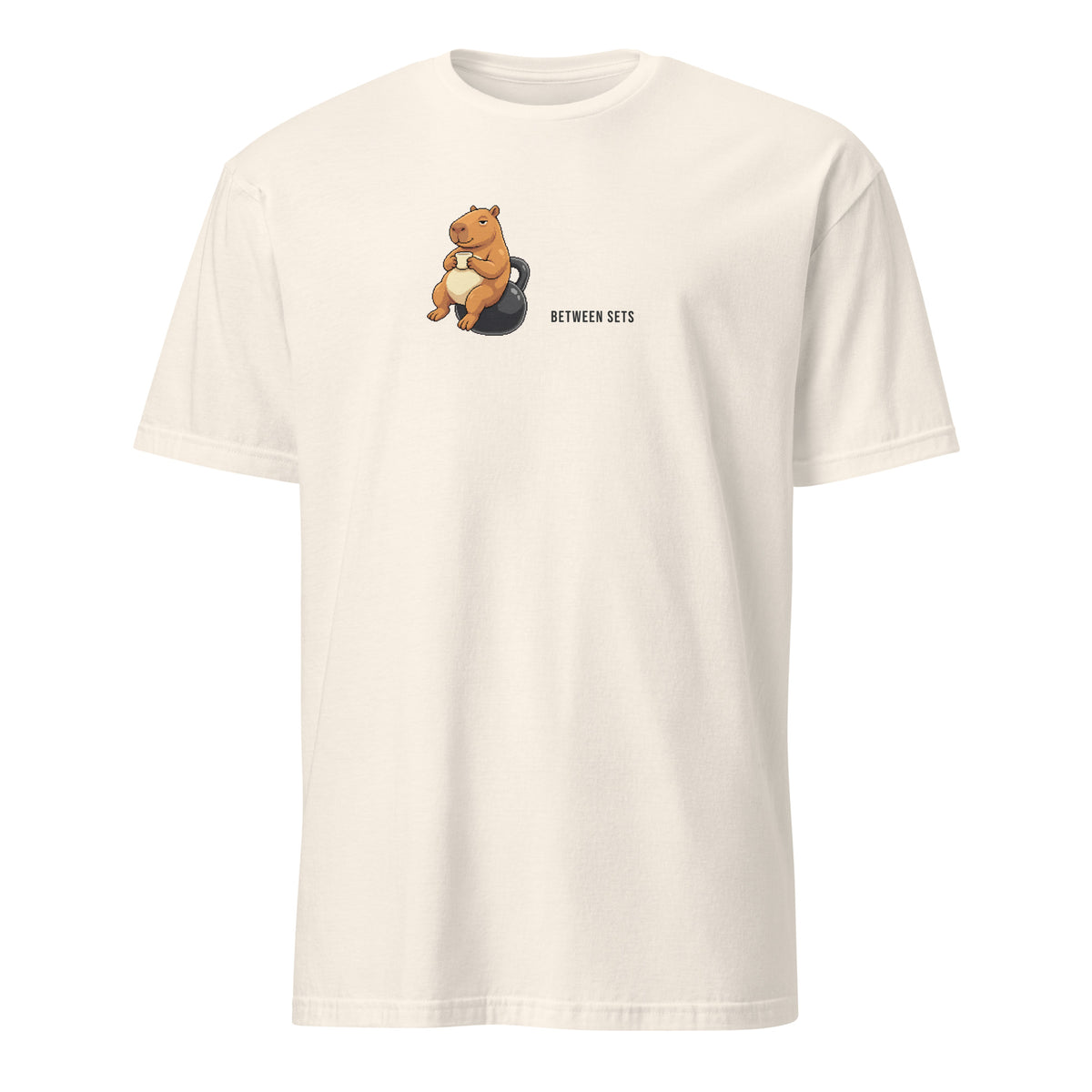 Between Sets Pixel Fitness Tee in Natural, with a seated capybara holding a cup on a kettlebell beside BETWEEN SETS lettering, front view