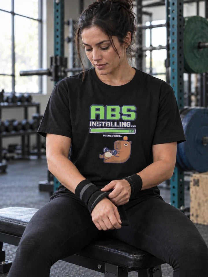 Woman wearing an Installing Abs tee while resting in a gym